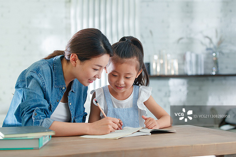 辅导女儿做作业的青年女人图片素材