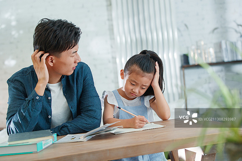 辅导女儿做作业的青年男人图片素材