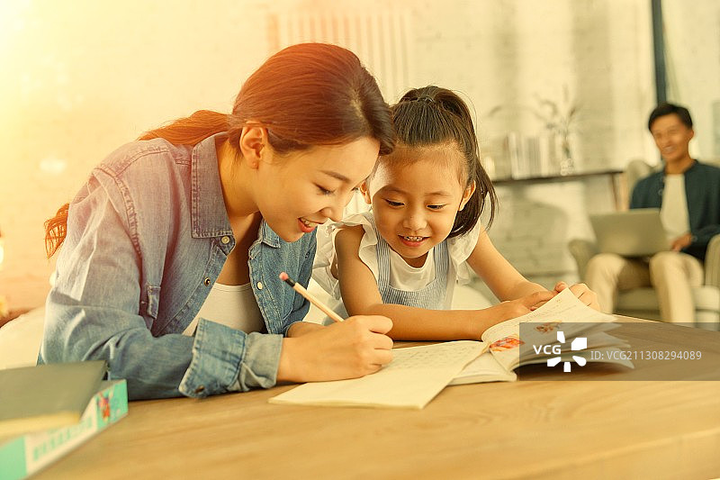 漂亮的青年女人辅导女儿写作业图片素材