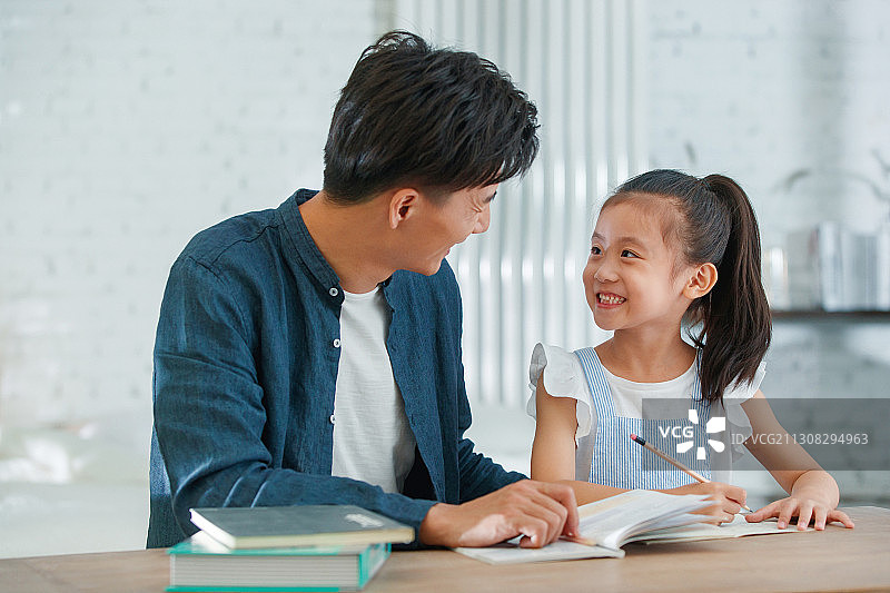 年轻父亲辅导女儿做功课图片素材