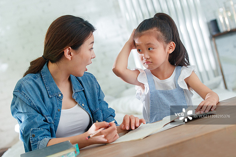 辅导女儿做作业的青年女人图片素材