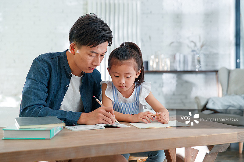 辅导女儿做作业的年轻爸爸图片素材
