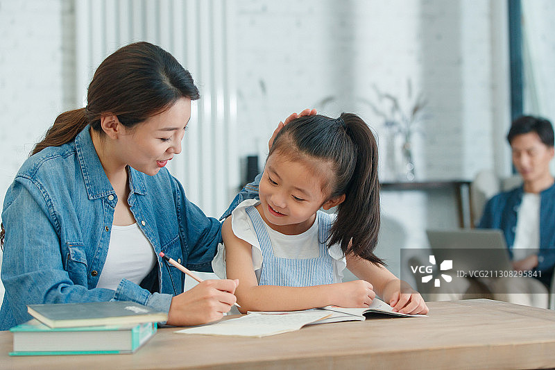 青年女人辅导女儿写作业图片素材
