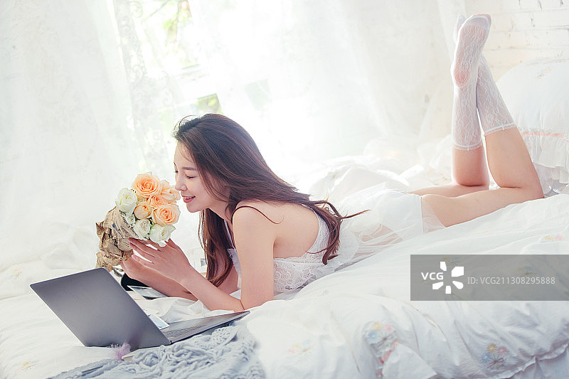 趴在床上度过闲暇时光的青年女人图片素材