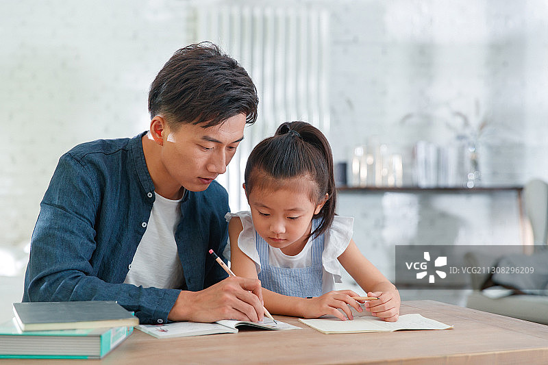 年轻父亲辅导女儿做功课图片素材