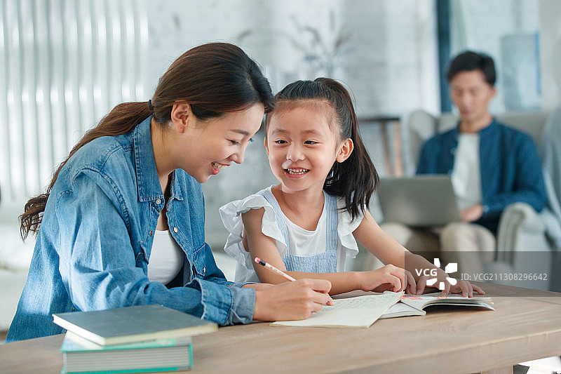 漂亮的青年女人辅导女儿写作业图片素材