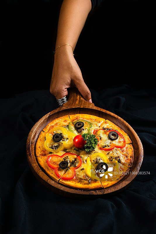 手中拿着披萨，黑色背景，印度马哈拉施特拉邦浦那图片素材