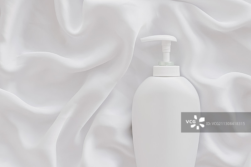 白色丝绸上空白标签化妆品容器瓶产品样机图片素材