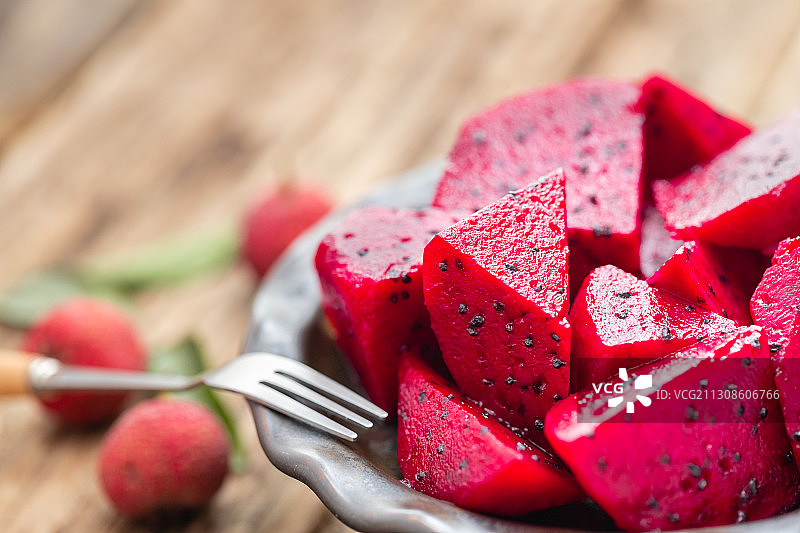 老木板上放着一盘切好的红心火龙果图片素材