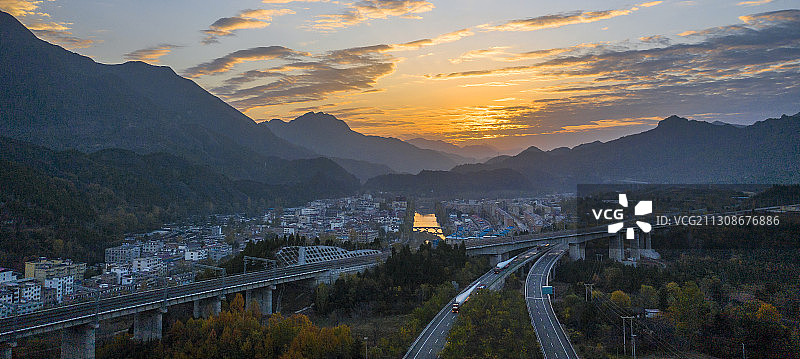 呼北高速公路和浩吉铁路迎着晨曦从一个小镇旁边伸向远方图片素材