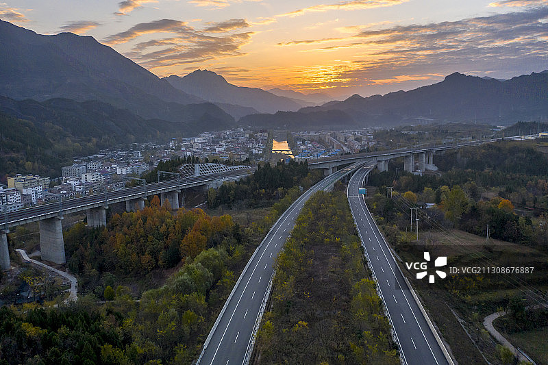 呼北高速公路和浩吉铁路迎着晨曦从一个小镇旁边伸向远方图片素材