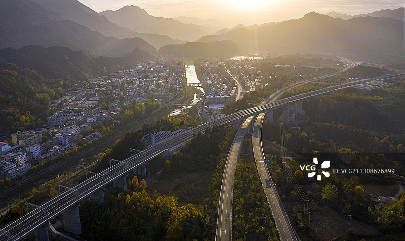 呼北高速公路和浩吉铁路迎着晨曦从一个小镇旁边伸向远方图片素材