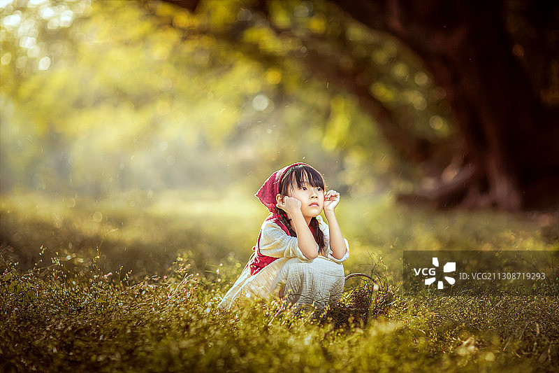 森林里穿连衣裙蹲着的小女孩图片素材