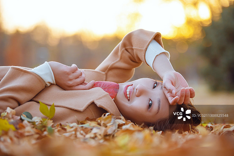 一个年轻女子躺在落叶中图片素材