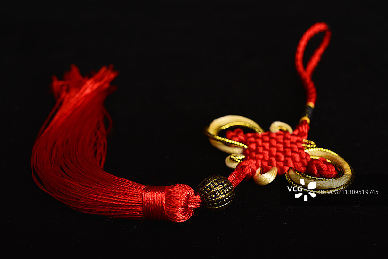 黑色背景下红色金色线绳编织绳艺中国结图片素材