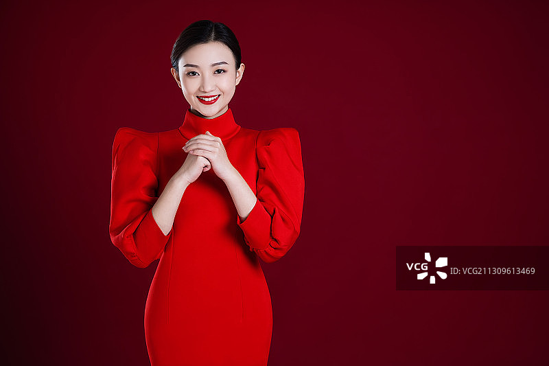 穿红裙的年青女子抱拳祝福图片素材