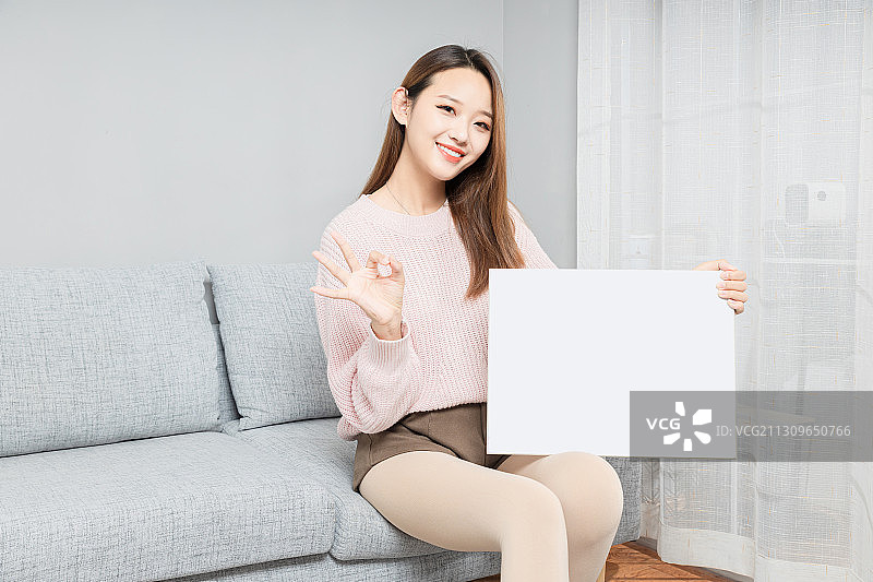 坐在沙发上,拿着白板的亚洲女孩图片素材