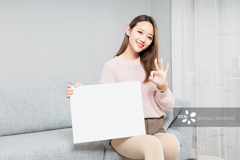 坐在沙发上,拿着白板的亚洲女孩图片素材