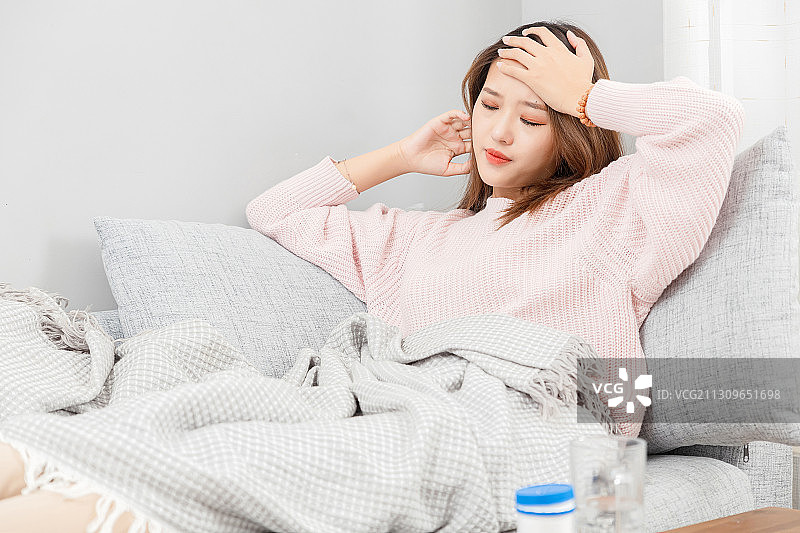 坐在沙发上感觉头晕的亚洲女孩图片素材