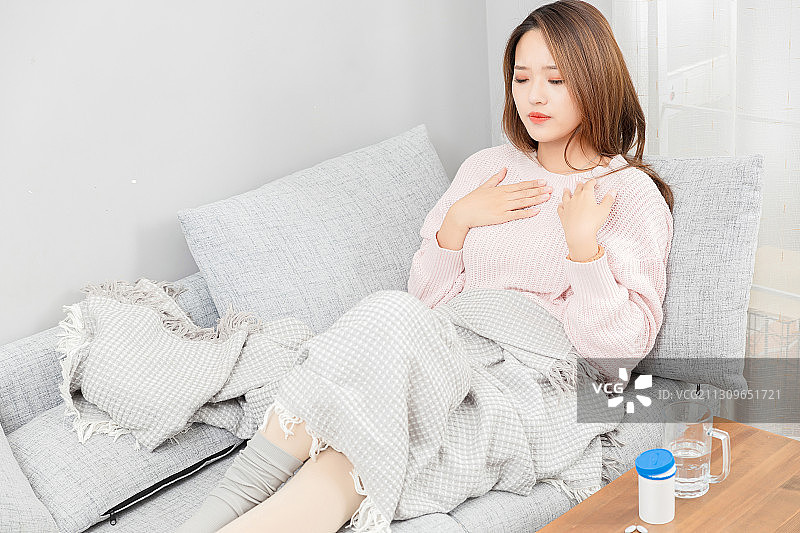 坐在沙发上咳嗽的亚洲女孩图片素材