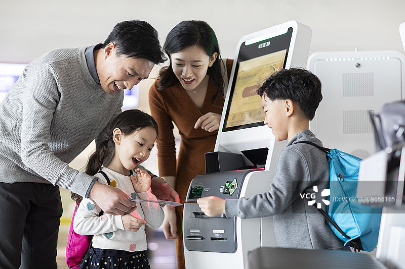 快乐的年轻家庭在机场自助值机图片素材
