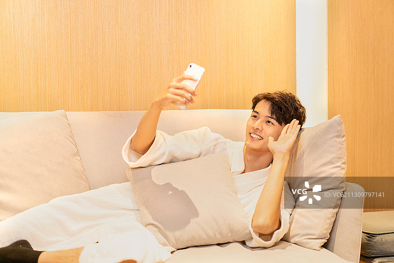 在客厅沙发上视频通话的男生图片素材