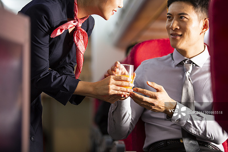 空姐给男商务乘客果汁在飞机机舱里特写图片素材