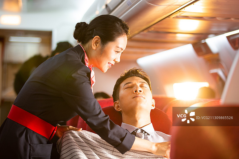 乘务员帮男商务乘客盖毯子图片素材