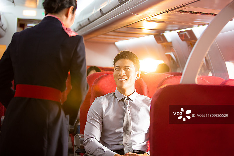 空姐和男商务乘客沟通在飞机机舱图片素材