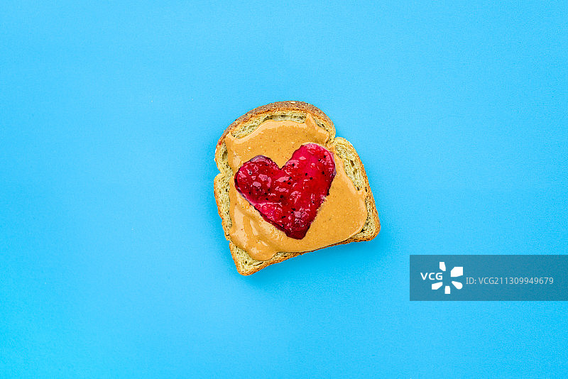 蓝色背景上花生酱三明治的心形果酱俯视图图片素材