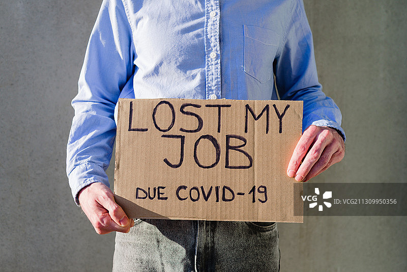 男人因新冠疫情失业后举着牌子的身体中部照片图片素材