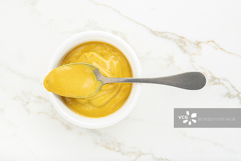 白色大理石桌上的碗和勺子里的芥末酱，顶视图图片素材