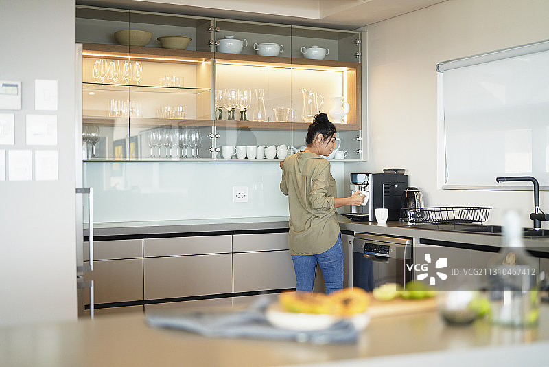 女人在现代家居厨房用咖啡机准备意式浓缩咖啡图片素材