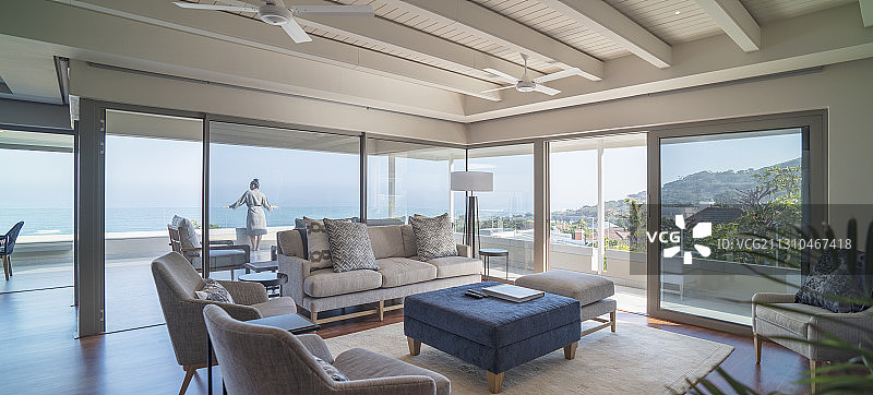 在豪华住宅的阳台上欣赏阳光明媚海景的女人图片素材