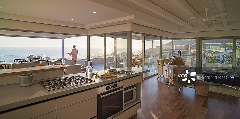 女子在豪华阳台上欣赏阳光明媚的海景图片素材