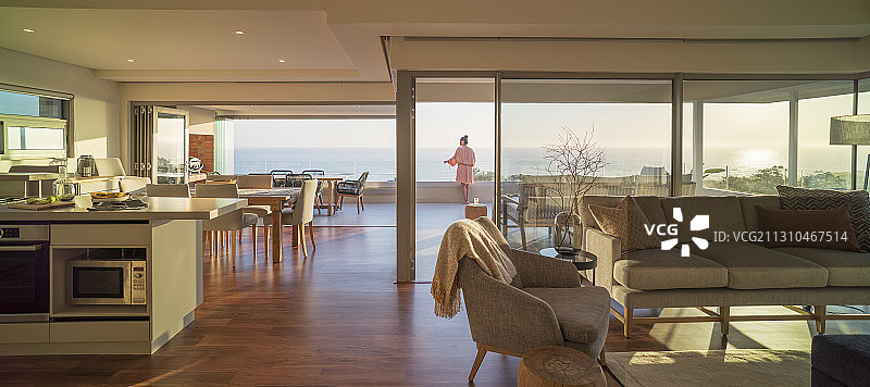 在豪华阳台上欣赏阳光明媚海景的女人图片素材