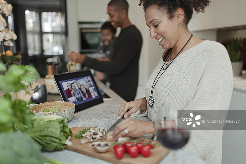 快乐的女人在厨房用平板电脑烹饪和视频聊天图片素材