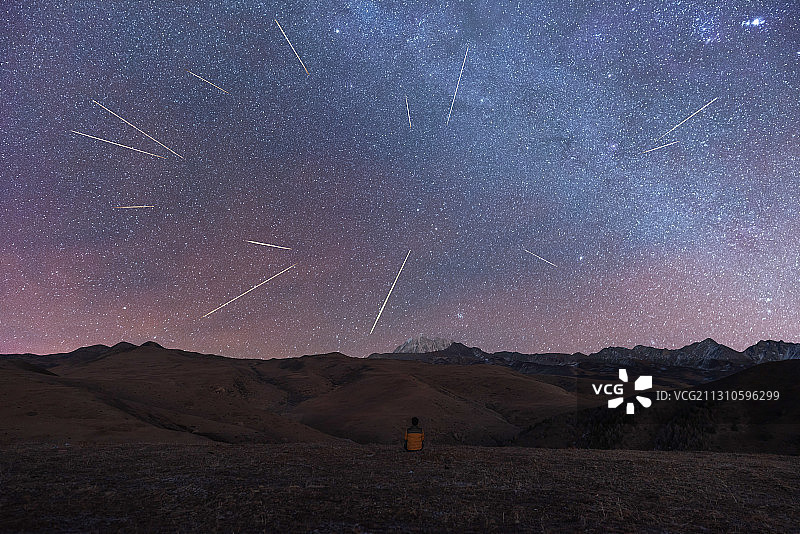 一个人坐在山头看雅拉雪山头顶的双子座流星雨图片素材