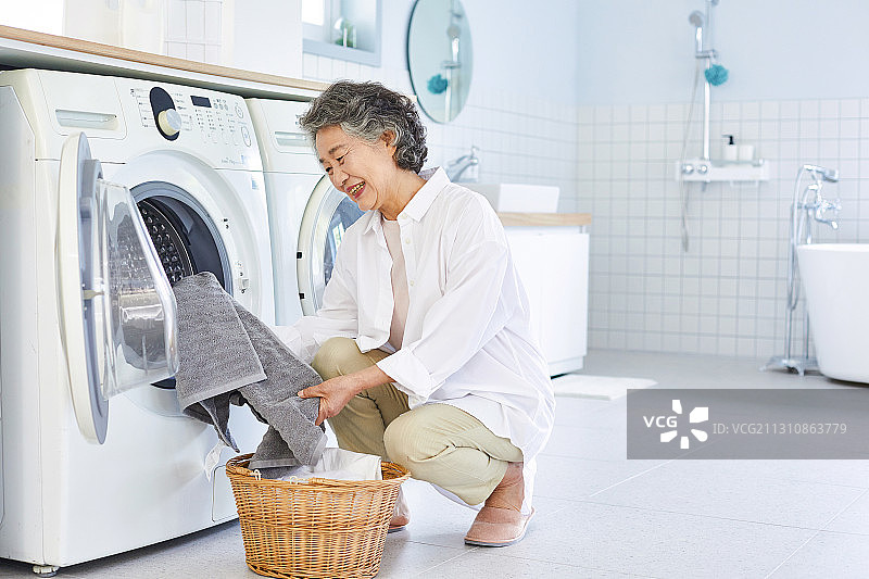 老年妇女在洗衣房使用洗衣机图片素材