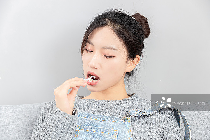 坐在沙发上,使用牙线的亚洲女孩图片素材