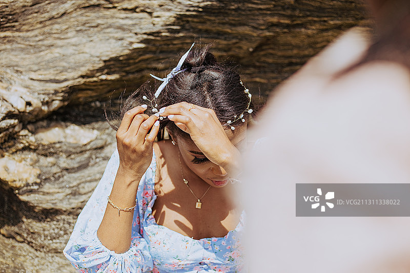 圭亚那年轻女子在加纳阿克拉海滩身穿连衣裙，整理花冠图片素材