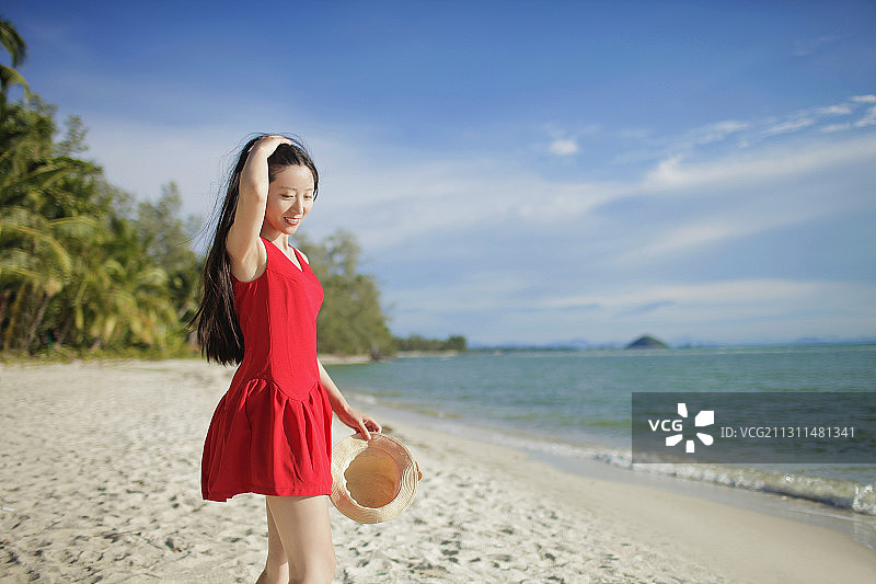 穿红裙的亚洲女子走在海边图片素材