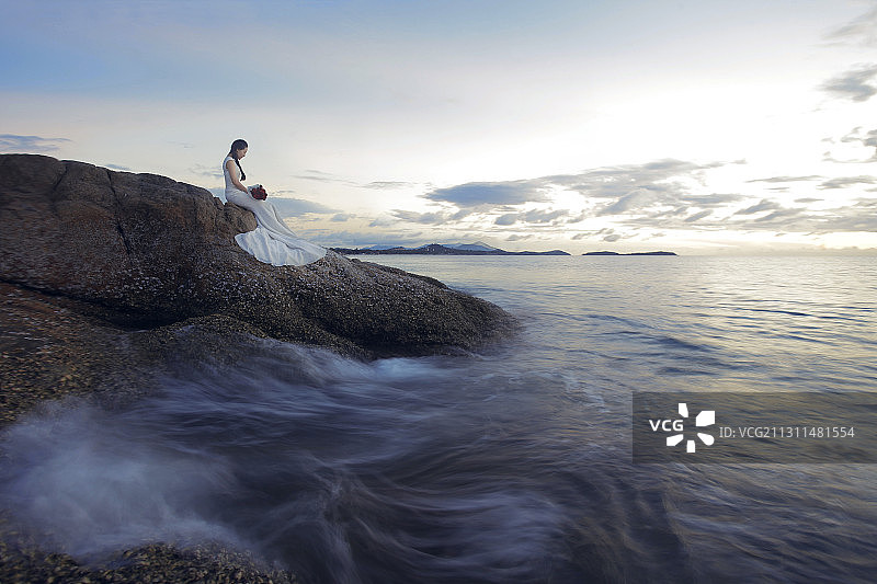 东方新娘坐在海边岩石上图片素材