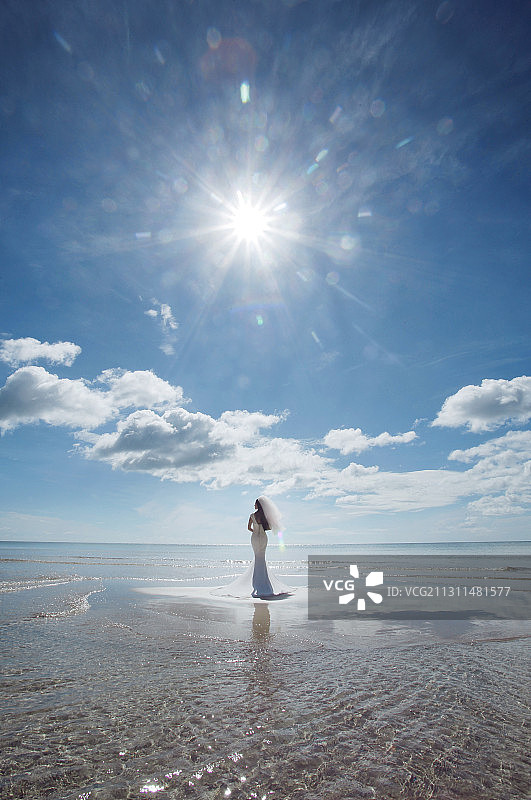 一个东方新娘手捧花站在海滩上图片素材