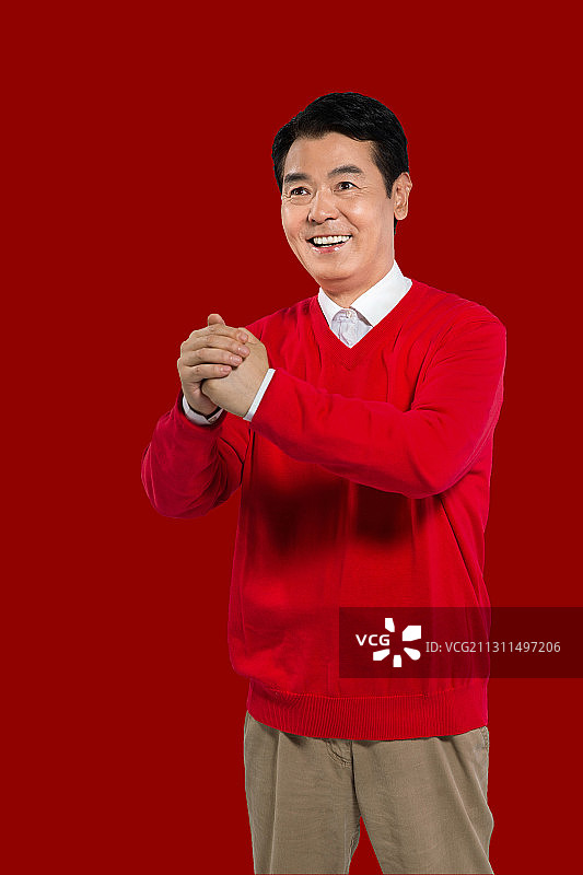 新年,红背景,身穿红色毛衣,抱拳拜年的喜庆男人图片素材