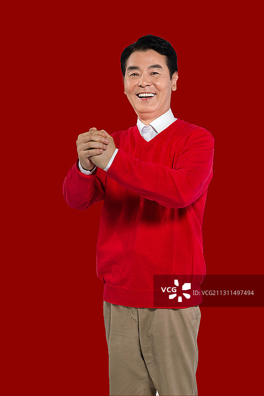新年,红背景,身穿红色毛衣,抱拳拜年的喜庆男人图片素材