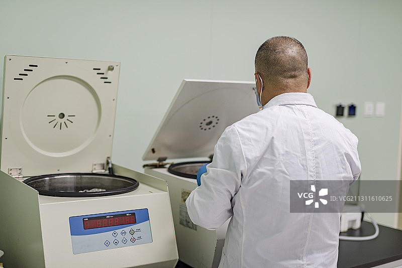 身穿白大褂的中年男性在医疗试验室内操作试验图片素材