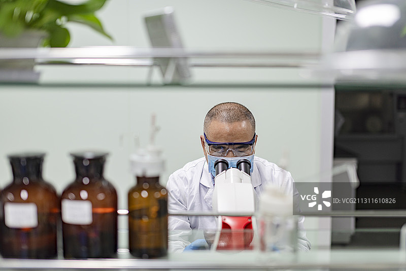 一中年男性医务工作者在试验台前观察试验图片素材