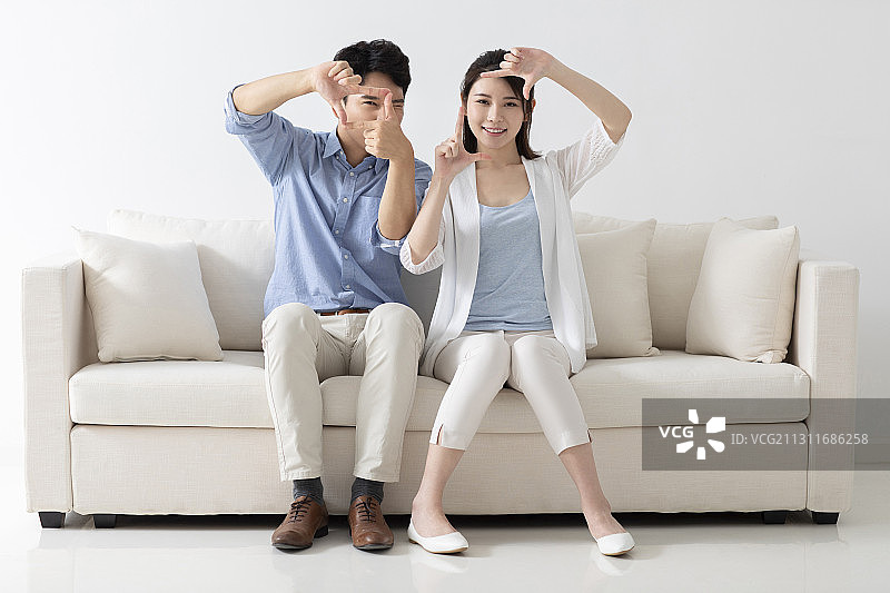 开心的年轻情侣坐在沙发上图片素材