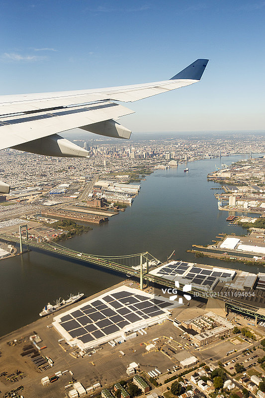 接近费城，经过特拉华河上的本杰明·富兰克林大桥，港口前沿的仓库覆盖着太阳能电池板，美国图片素材